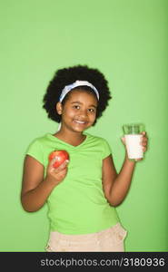 African American girl holding glass of milk and apple.