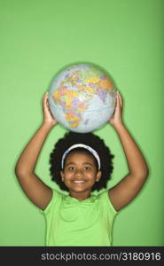 African American girl holding globe on top of head and smiling at viewer.