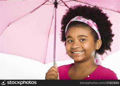 African American girl holding pink umbrella smiling at viewer.