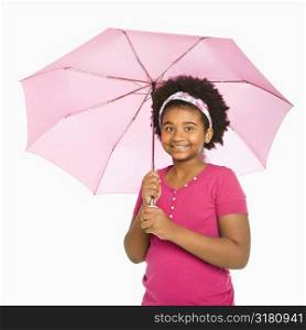 African American girl holding pink umbrella smiling at viewer.