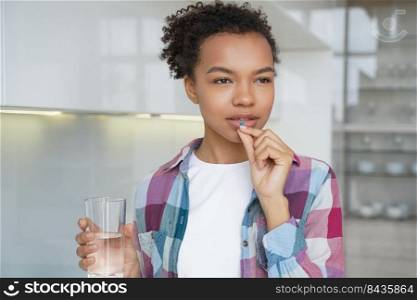 African american girl is taking medicine drug. Hispanic teenage girl is taking vitamins or painkillers. Medications and pharmaceutical treatment. Disease prevention, contraceptive pills taking.. African american girl is taking medicine drug. Disease prevention, contraceptive pills taking.