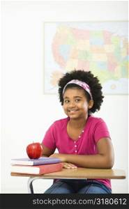 African American girl sitting in school desk smiling at viewer.