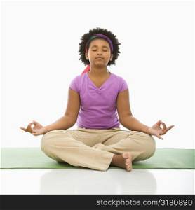 African American girl sitting on floor in yoga lotus posture with eyes closed.