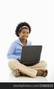 African American girl sitting on floor using laptop and smiling at viewer.