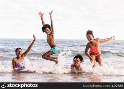 african American,group of children or brothers and sisters jump into the sea happily while traveling with family or at school during summer or vacation after unlocking down from COVID 19.