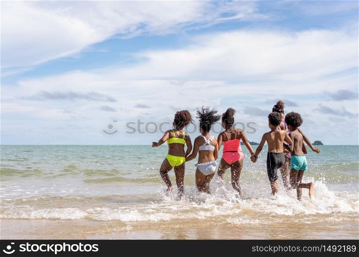 African American,group of children or brothers and sisters wear swimming suits And carried hands into the sea with fun during the holidays or summer, in school or family