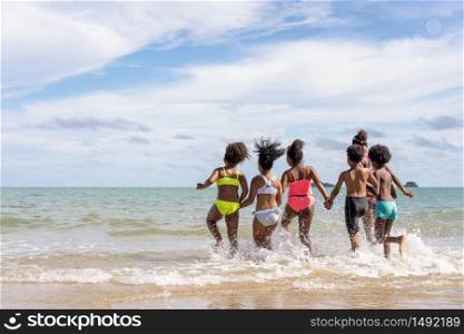 African American,group of children or brothers and sisters wear swimming suits And carried hands into the sea with fun during the holidays or summer, in school or family