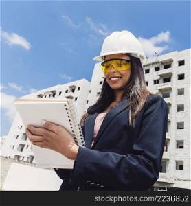 african american lady safety helmet with notebook near building construction