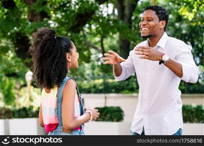 African american little girl with her father having good time together outdoors on the street.