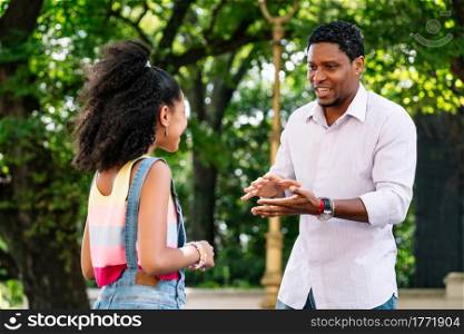 African american little girl with her father having good time together outdoors on the street.