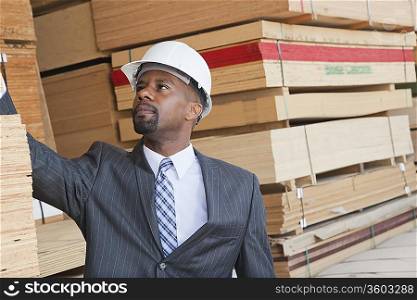 African American male engineer inspecting wooden planks
