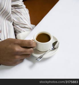 African American male hand holding handle of expresso cup.
