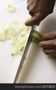 African-American male hands using large kitchen knife to chop fennel.