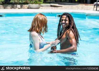 African-American man and white woman playing in a pool.