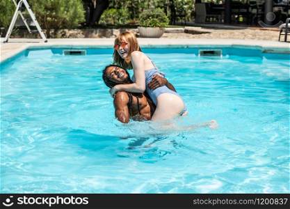 African-American man and white woman playing in a pool.