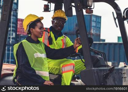 African american man and woman driving forklift in shipyard . Logistics supply chain management and international goods export concept .. African american man and woman driving forklift in shipyard .