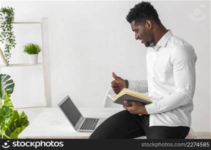 african american man having video call holding book