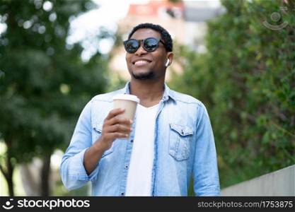 African american man holding a cup of coffee while standing outdoors on the street. Urban concept.