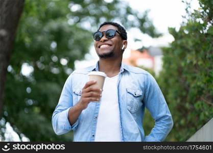 African american man holding a cup of coffee while standing outdoors on the street. Urban concept.