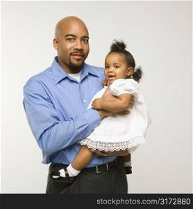African American man holding infant girl standing against white background.