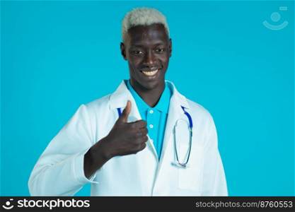 African american man in medical white coat showing thumbs up sign over blue background. Positive doctor smiles to camera. Winner. Success. Body language. African american man in medical white coat showing thumbs up sign over blue background. Positive doctor smiles to camera. Winner. Success. Body language.