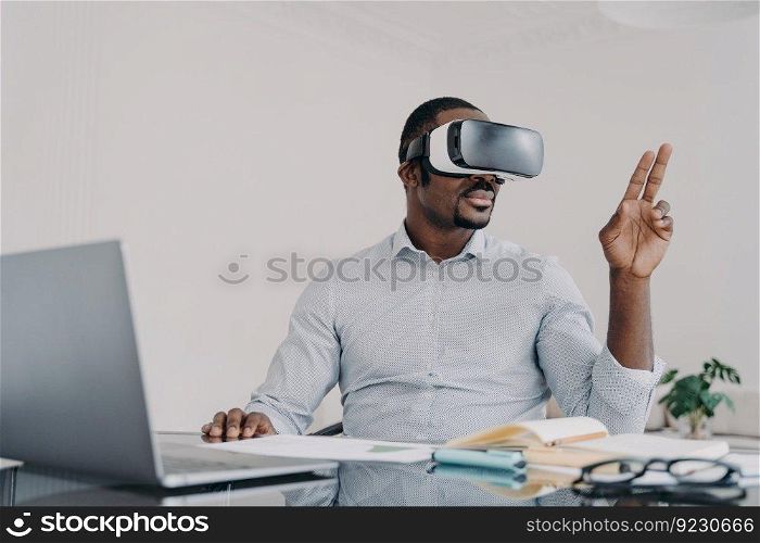 African american man in vr glasses. Businessman has virtual meeting. Freelancer is working on design project on laptop. Modern digital technology and electronic devices for business and creativity.. African american man in vr glasses. Modern digital technology for business and creativity.