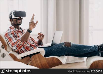 African american man in vr headset enjoying the vision at home office. Businessman has virtual meeting. Relaxed freelancer is sitting in chair and working on project. High tech digital technology.. African freelancer in vr headset enjoying the vision at home. Businessman has virtual meeting.