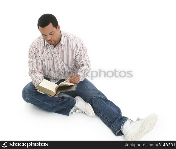 African American man reading book. Casual clothing. Sitting on floor. Over white.