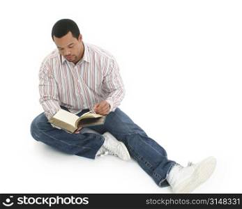 African American man reading book. Casual clothing. Sitting on floor. Over white.