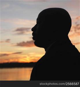 African-American man standing by water at sunset in Washington, DC, USA.