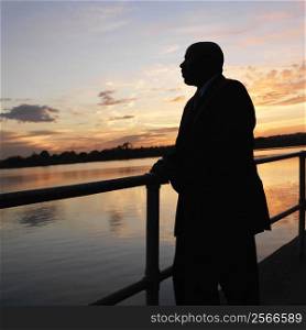 African-American man standing by water at sunset in Washington, DC, USA.