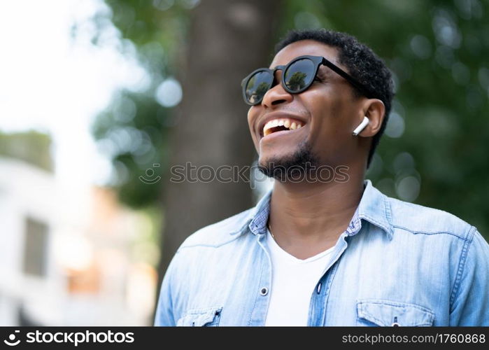 African american man wearing sunglasses and smiling while walking outdoors on the street. Urban concept.