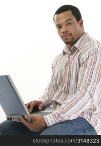 African American man with laptop computer. Casual clothes. Sitting on stool.