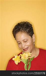 African American mature adult female holding flowers.