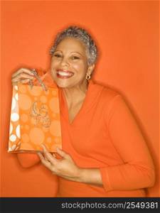 African American mature adult female holding gift bag.