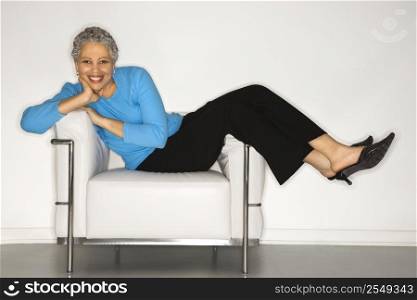 African American mature adult female lying back on chair.