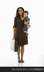 African American mid adult businesswoman holding toddler son on hip smiling at viewer.