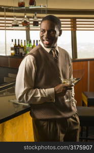 African American mid adult man standing at bar with martini.