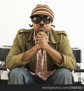 African-American mid-adult man wearing hat and sunglasses and looking at viewer.