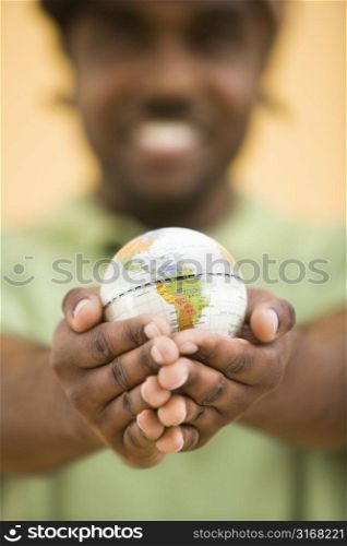 African-American mid-adult man wearing hat holding small globe toviewer.