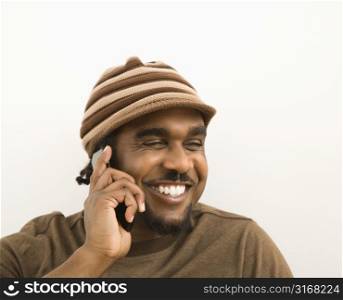African-American mid-adult man wearing hat talking on cell phone.