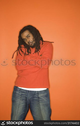 African-American mid-adult man with crossed arms and attitude wearing orange clothing on orange background.