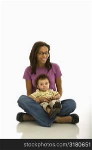African American mid adult mom sitting with toddler son on lap looking at viewer.
