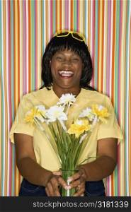 African-American mid-adult woman laughing holding flowers.