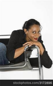 African American mid-adult woman lounging in chair smiling and looking at viewer.