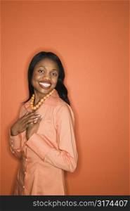 African-American mid-adult woman on orange background wearing orange clothing.