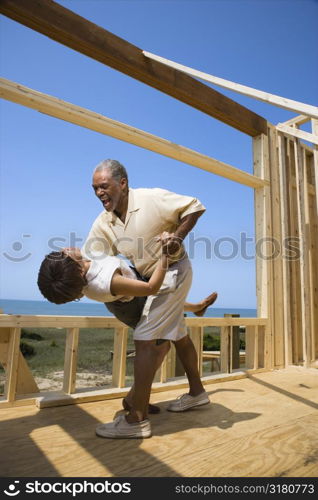 African American middle aged couple dancing in new home construction at beach.