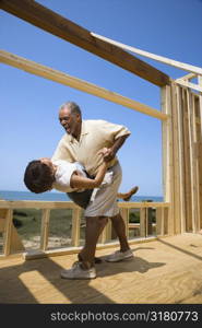 African American middle aged couple dancing in new home construction at beach.