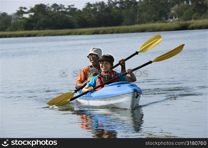 African American middle-aged couple smiling and paddling kayak.