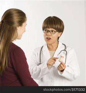 African American middle-aged female doctor explaining medication to Caucasian mid-adult female patient.